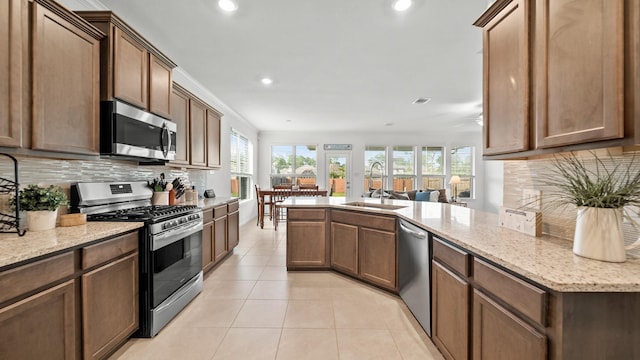 kitchen with decorative backsplash, stainless steel appliances, light stone countertops, and sink