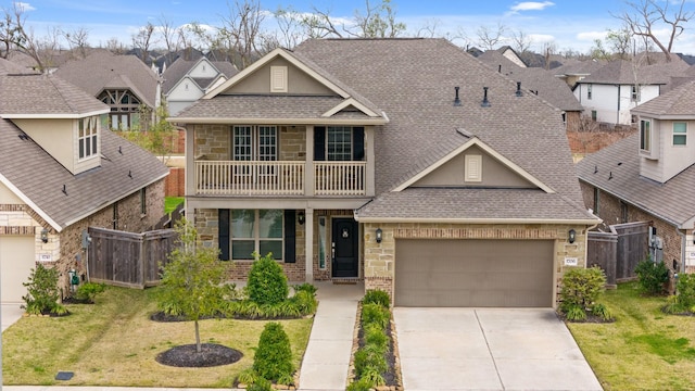 view of front facade featuring a shingled roof, a front yard, fence, a balcony, and driveway