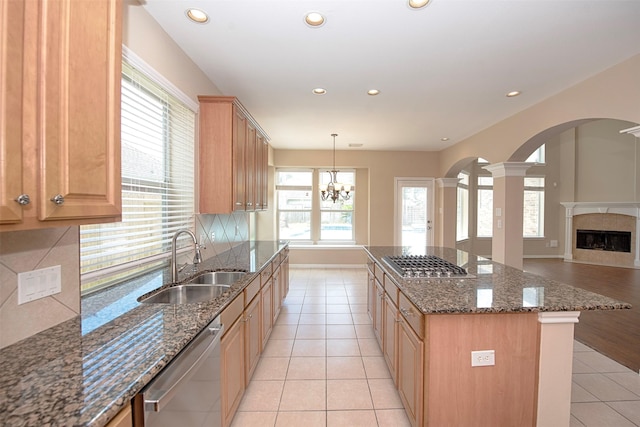 kitchen with appliances with stainless steel finishes, dark stone counters, sink, a chandelier, and a center island