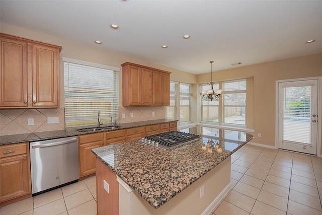 kitchen featuring sink, a center island, stainless steel appliances, a notable chandelier, and dark stone countertops