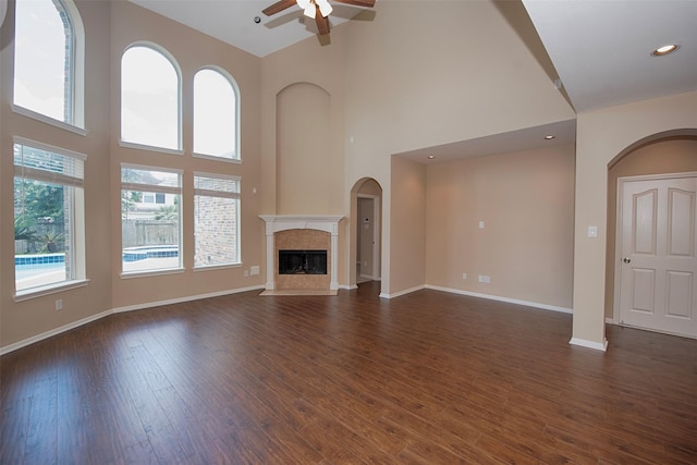 unfurnished living room with ceiling fan, a healthy amount of sunlight, and a high ceiling