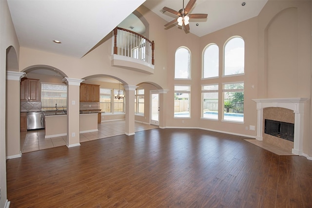 unfurnished living room with hardwood / wood-style floors, a towering ceiling, and ceiling fan