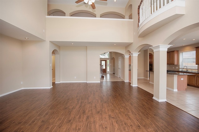 unfurnished living room with sink, wood-type flooring, and a high ceiling