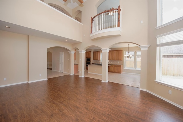 unfurnished living room with an inviting chandelier, a high ceiling, and light wood-type flooring