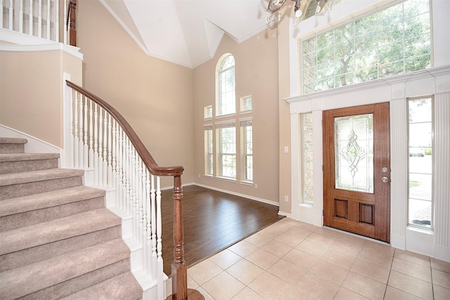 entryway featuring a towering ceiling, ornamental molding, and light tile patterned flooring