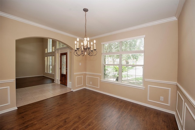 empty room with hardwood / wood-style flooring, an inviting chandelier, and ornamental molding