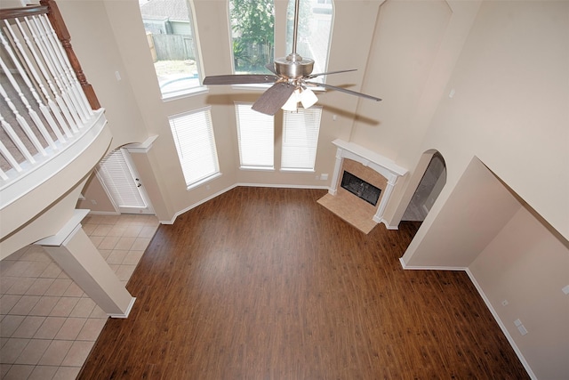 unfurnished living room featuring a fireplace, a wealth of natural light, light hardwood / wood-style flooring, and ceiling fan