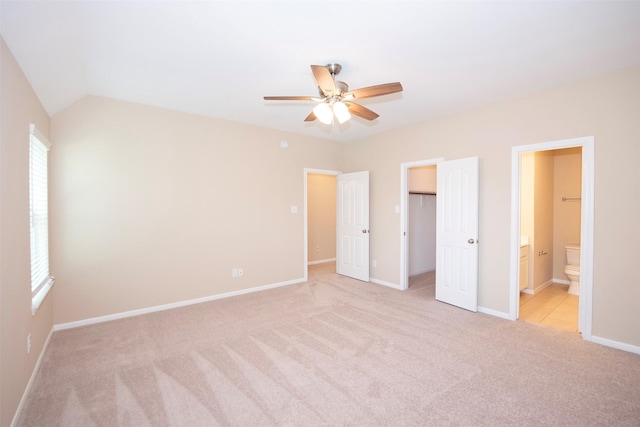 unfurnished bedroom with ensuite bathroom, light colored carpet, ceiling fan, a closet, and lofted ceiling