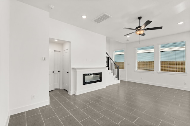 unfurnished living room featuring ceiling fan, baseboards, a glass covered fireplace, and visible vents