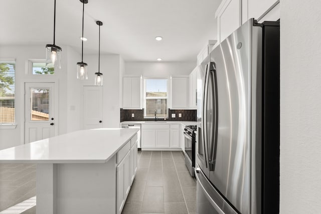 kitchen featuring tasteful backsplash, white cabinets, a sink, appliances with stainless steel finishes, and tile patterned floors