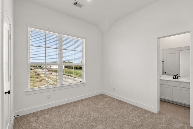 unfurnished bedroom featuring connected bathroom, light colored carpet, visible vents, a sink, and baseboards