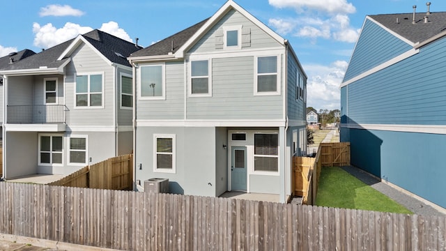 view of front of house with central AC, a fenced backyard, a gate, and stucco siding