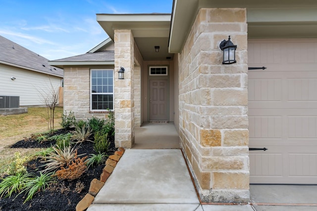 view of exterior entry featuring a garage and cooling unit