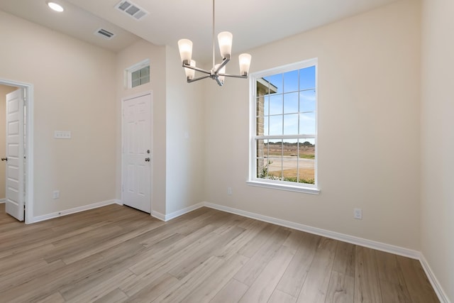 spare room featuring a notable chandelier and light hardwood / wood-style floors