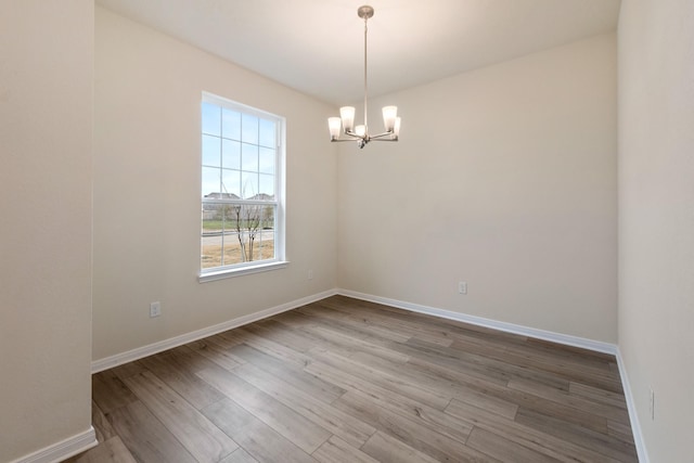 empty room with hardwood / wood-style floors and a chandelier