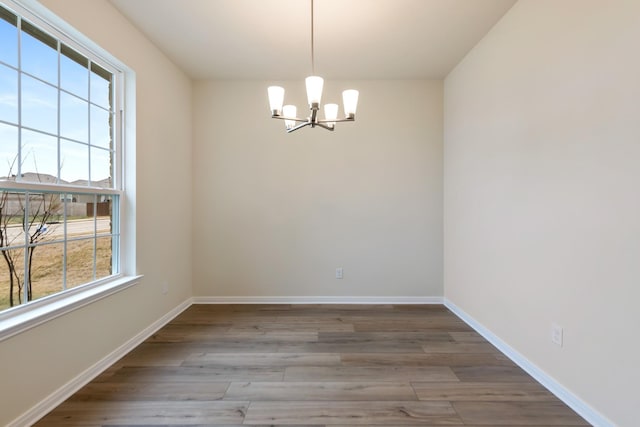 spare room with an inviting chandelier and light hardwood / wood-style floors