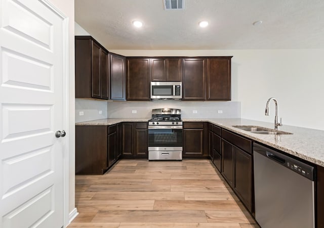 kitchen featuring appliances with stainless steel finishes, sink, light stone counters, and kitchen peninsula