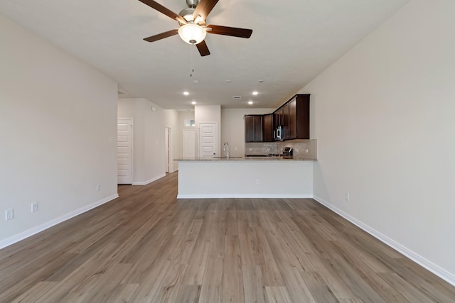 unfurnished living room with ceiling fan, sink, and light hardwood / wood-style flooring