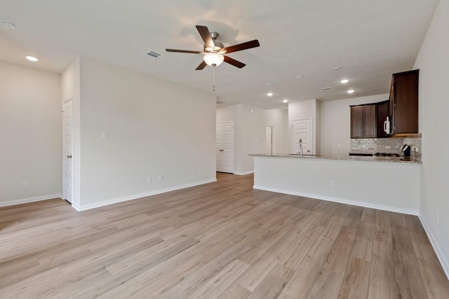 unfurnished living room with ceiling fan, sink, and light hardwood / wood-style floors