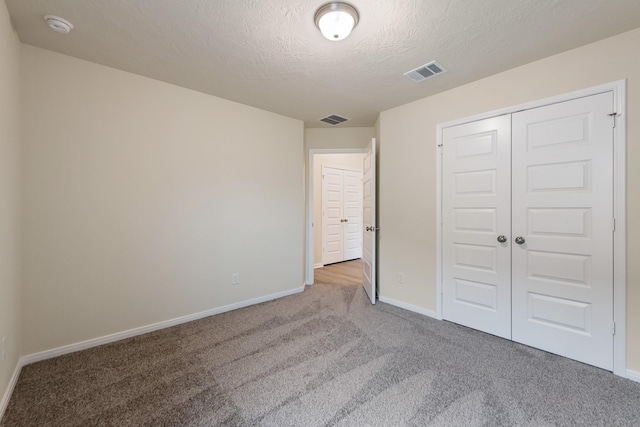 unfurnished bedroom with carpet, a textured ceiling, and a closet