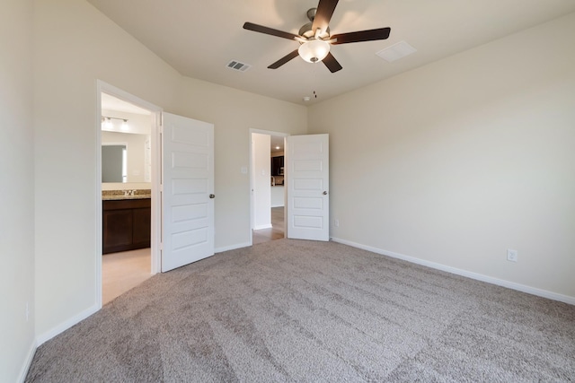 unfurnished bedroom with ceiling fan, light colored carpet, and ensuite bath