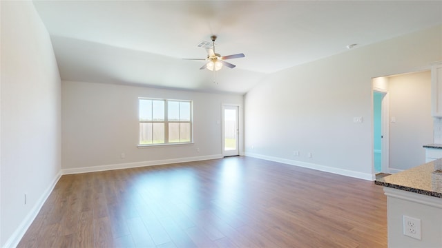 empty room with vaulted ceiling, dark hardwood / wood-style floors, and ceiling fan