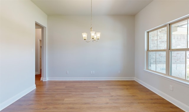 unfurnished room with hardwood / wood-style flooring and an inviting chandelier