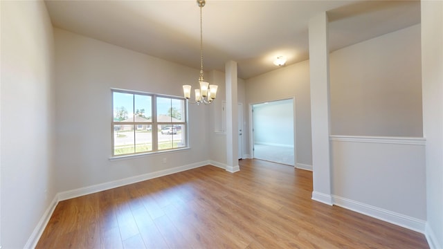 spare room featuring hardwood / wood-style flooring and a chandelier