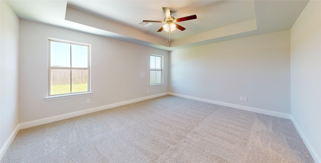 unfurnished room with light carpet, a raised ceiling, and ceiling fan