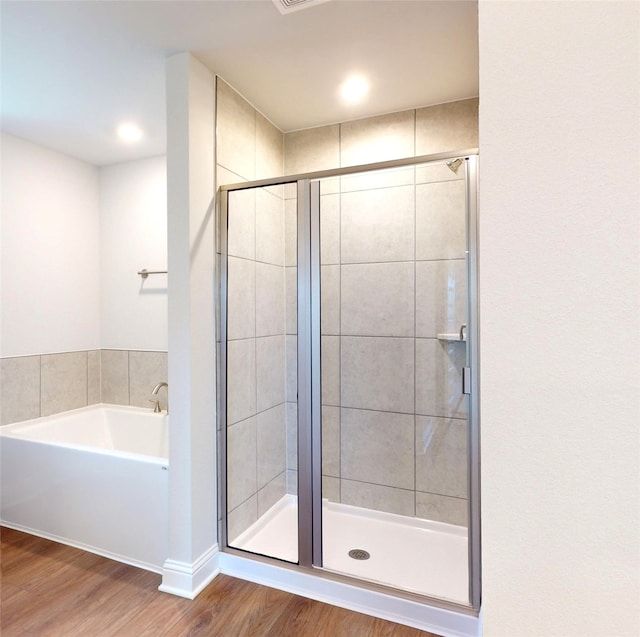 bathroom with independent shower and bath and hardwood / wood-style floors