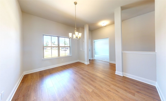 unfurnished room with an inviting chandelier and hardwood / wood-style floors