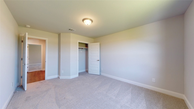 unfurnished bedroom featuring light carpet and a closet