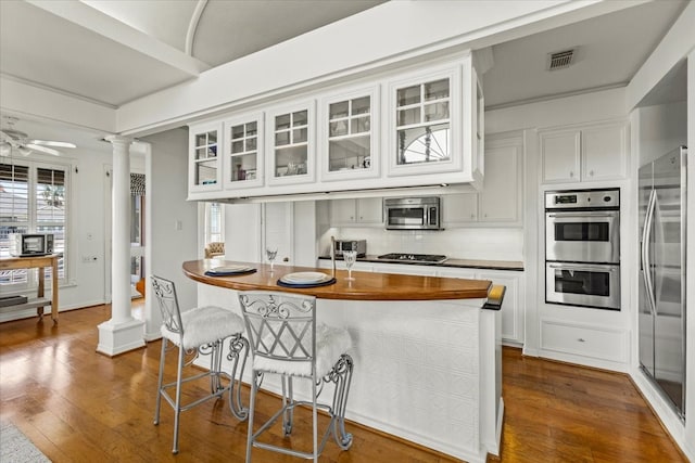 kitchen with white cabinetry, stainless steel appliances, decorative columns, tasteful backsplash, and dark hardwood / wood-style flooring