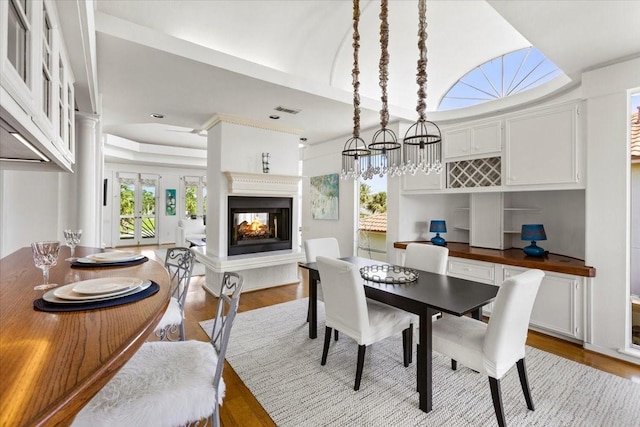 dining area featuring a multi sided fireplace and light hardwood / wood-style floors