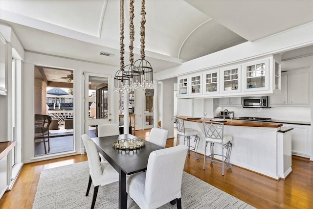 dining room featuring vaulted ceiling, a chandelier, and light hardwood / wood-style floors