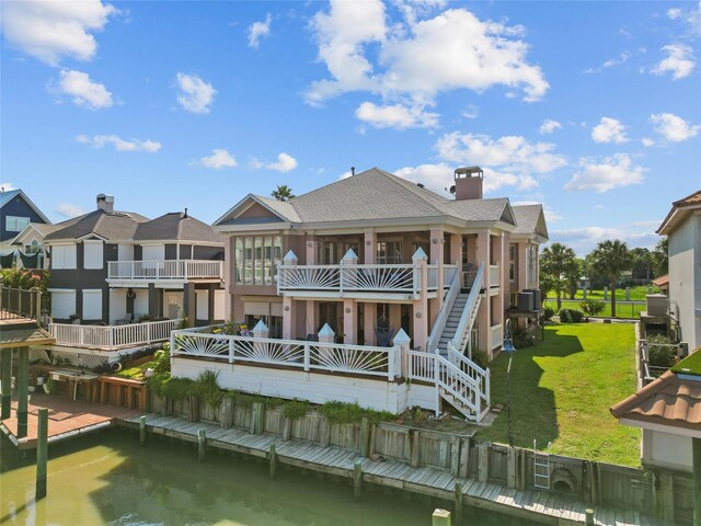 back of house with a balcony, a water view, and a yard