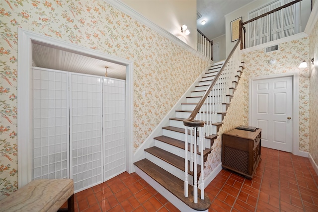 stairs featuring crown molding and an inviting chandelier