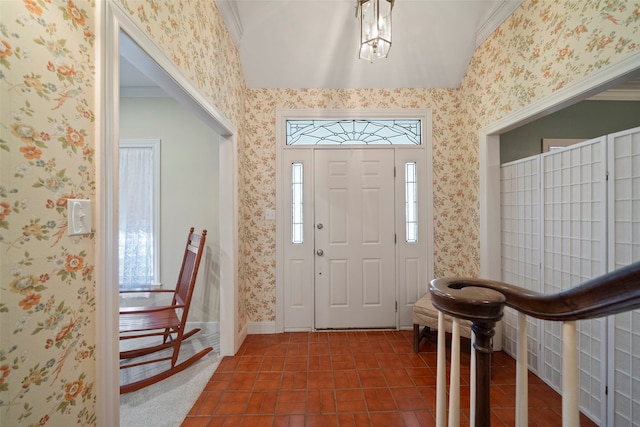 foyer entrance with dark tile patterned floors and ornamental molding