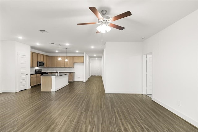 kitchen featuring a center island with sink, appliances with stainless steel finishes, ceiling fan, dark hardwood / wood-style floors, and decorative light fixtures