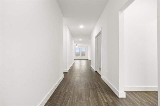hall featuring dark wood finished floors, baseboards, and recessed lighting