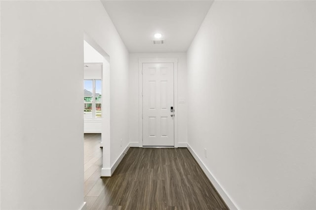 hallway with visible vents, baseboards, and dark wood-style flooring