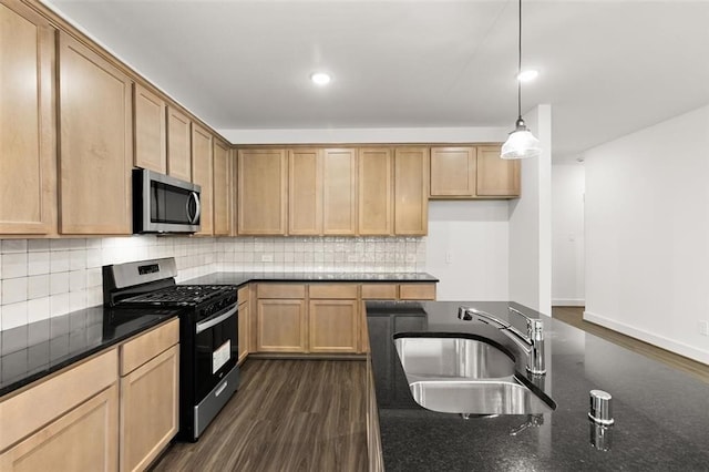 kitchen with hanging light fixtures, a sink, decorative backsplash, stainless steel appliances, and dark wood finished floors