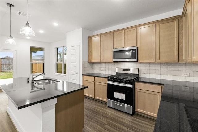 kitchen with dark countertops, a sink, stainless steel appliances, visible vents, and dark wood-style floors