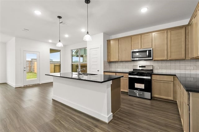 kitchen featuring dark countertops, backsplash, appliances with stainless steel finishes, and a sink