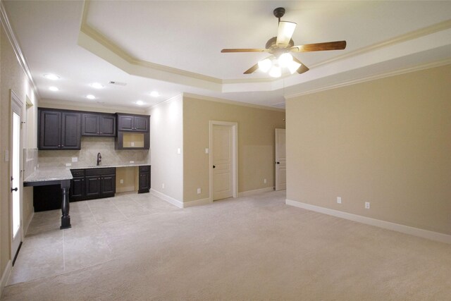 kitchen featuring ceiling fan, a raised ceiling, backsplash, and ornamental molding