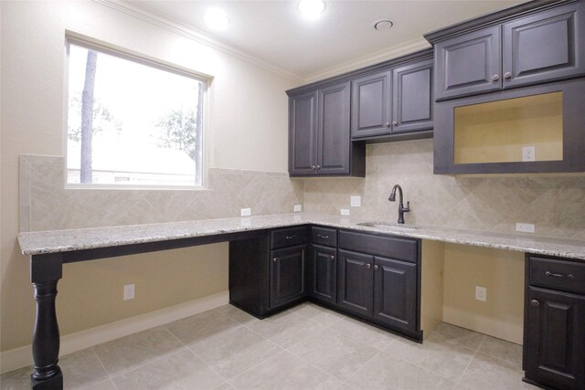 kitchen featuring crown molding, tasteful backsplash, light stone counters, light tile floors, and sink