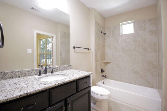 full bathroom featuring tiled shower / bath combo, plenty of natural light, toilet, and vanity