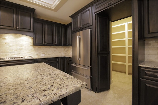 kitchen with stainless steel appliances, light stone counters, dark brown cabinets, and tasteful backsplash