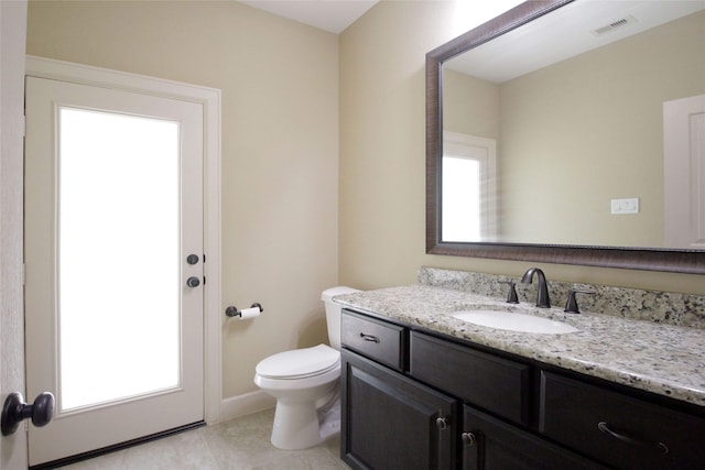 bathroom with tile flooring, a wealth of natural light, toilet, and vanity