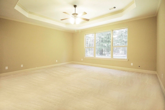 carpeted spare room with a tray ceiling, crown molding, and ceiling fan